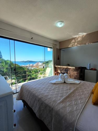 a bedroom with a large bed with a large window at Suíte com vista panorâmica in Bombinhas