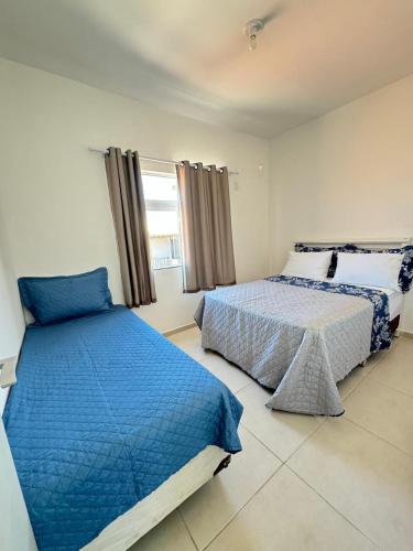 2 Betten in einem Schlafzimmer mit blau und weiß in der Unterkunft Casa brisa do mar in Arraial do Cabo