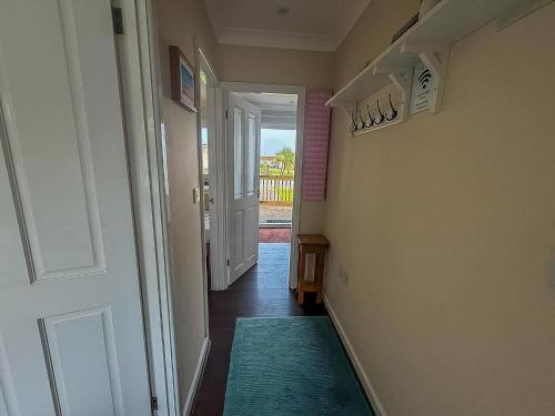 a hallway with a door and a green rug at Chalet For Hire At Rainbows End Near A Beautiful Norfolk Beach Ref 31039R in Bacton
