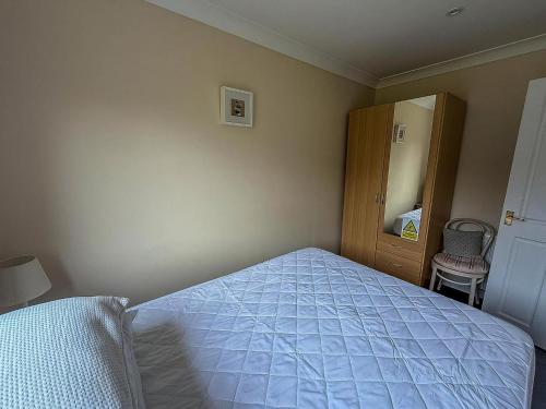 a bedroom with a bed and a cabinet and a mirror at Chalet For Hire At Rainbows End Near A Beautiful Norfolk Beach Ref 31039R in Bacton