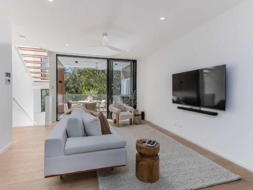 a living room with a couch and a flat screen tv at Urbanstayz - Lakehouse No 4- Luxury Lakefront Getaway Villa Pet Friendly in Cabarita Beach