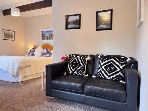 a black leather couch in a bedroom with a bed at Swan House in Martinborough 