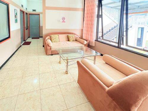 a living room with two couches and a glass table at RedDoorz Syariah at Nusa Indah near BNS in Batu