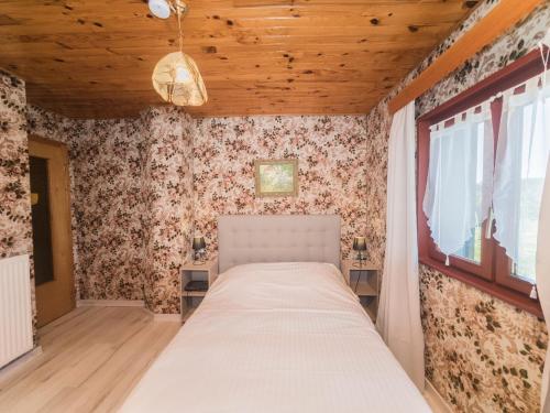 - une chambre avec un lit dans une pièce ornée de papier peint floral dans l'établissement House in Vosges near Cascades du Gerhard, cleaning included, à Girmont-Val-d'Ajol