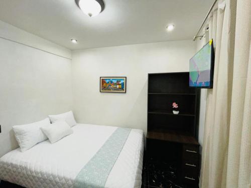 a bedroom with a white bed and a tv at casa Borde Del Lago1 in Panajachel