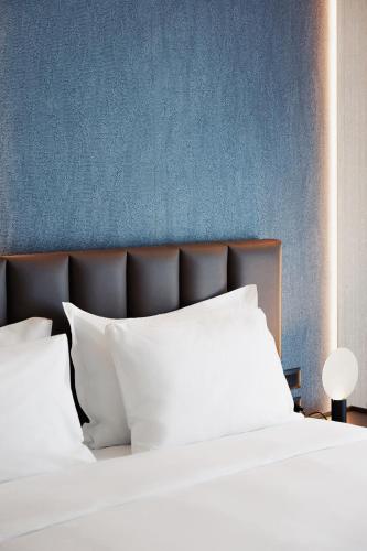 a bed with white pillows and a blue wall at Grand Duka Hotel & SPA in Durrës