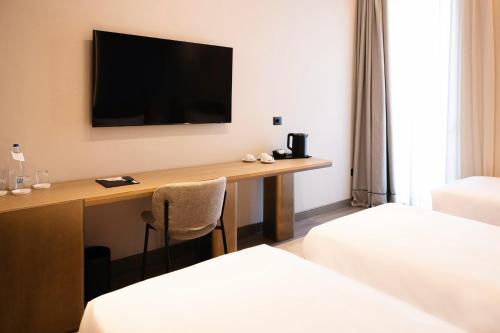 a hotel room with a desk with a television on the wall at Grand Duka Hotel & SPA in Durrës