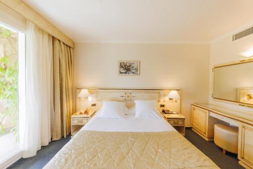 a hotel room with a bed and a large window at Hotel Corsica & Spa Serena in Calvi