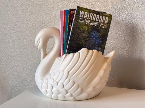 a white vase sitting on a shelf next to a book at Swan House in Martinborough 