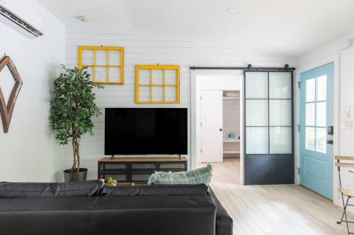a living room with a black couch and a flat screen tv at Tranquility Pond Cottage, Relax, Fish and Unwind in Buford