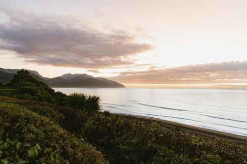 a view of the ocean with mountains in the background at Surfwatch House in Kaikoura