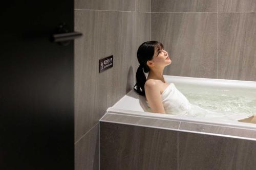 a woman is sitting in a bath tub at Aank Hotel and Spa Daejeon Yuseong in Daejeon