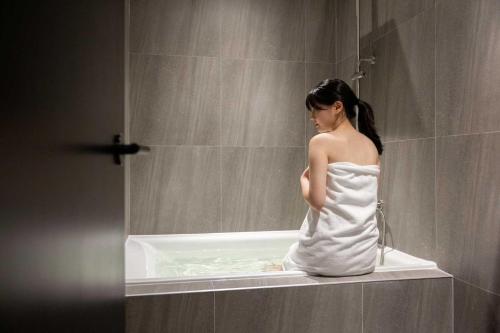 a woman is sitting in a bath tub at Aank Hotel and Spa Daejeon Yuseong in Daejeon