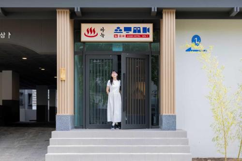 大田Aank Hotel and Spa Daejeon Yuseong的站在建筑物门口的女人
