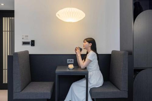 a woman sitting at a table talking on a cell phone at Aank Hotel and Spa Daejeon Yuseong in Daejeon