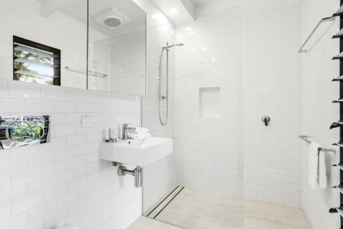 Un baño blanco con lavabo y ducha. en Coastal Luxe Little Cove Noosa, en Noosa Heads
