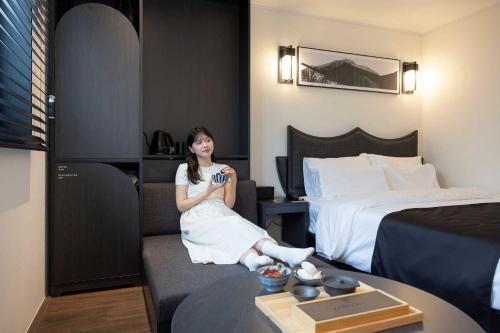 a woman sitting on a couch in a hotel room at Aank Hotel and Spa Daejeon Yuseong in Daejeon