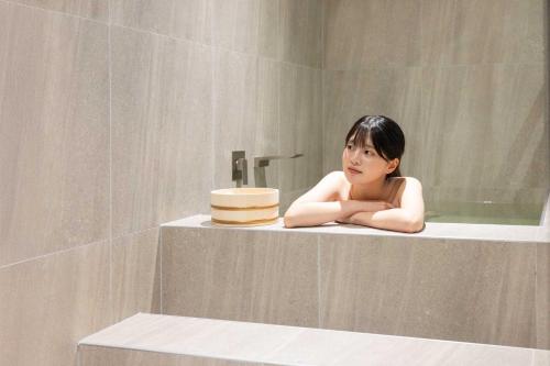 a woman laying in a bath tub in a bathroom at Aank Hotel and Spa Daejeon Yuseong in Daejeon
