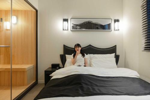 a woman sitting on top of a bed at Aank Hotel and Spa Daejeon Yuseong in Daejeon