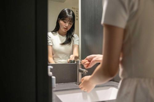 a woman standing in front of a bathroom mirror at Aank Hotel and Spa Daejeon Yuseong in Daejeon