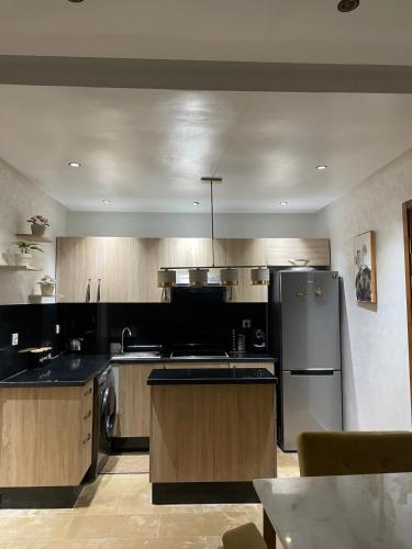 Una cocina con refrigerador de acero inoxidable y gabinetes de madera. en Beautiful apartment with pool, en Minaret de Mansuria