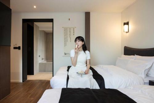 a woman sitting on a bed in a hotel room at Aank Hotel and Spa Daejeon Yuseong in Daejeon