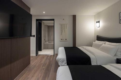 a hotel room with two beds and a flat screen tv at Aank Hotel and Spa Daejeon Yuseong in Daejeon