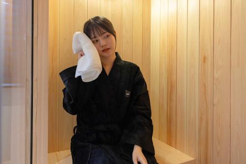 a woman holding a large white sock in a room at Aank Hotel and Spa Daejeon Yuseong in Daejeon