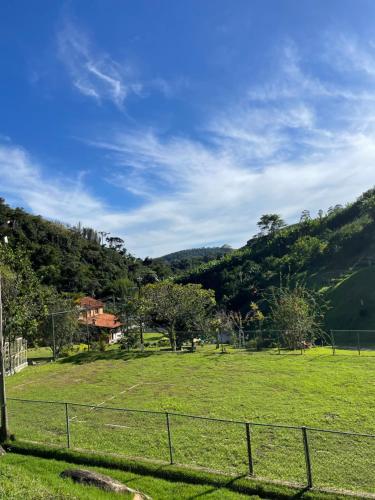a field with a fence in front of a mountain at Refúgio da Mata - Chalé Araucária in Paty do Alferes