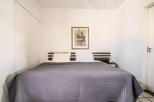 a bedroom with a bed with a purple comforter at Flat c/ Limpeza Diária | Piscina e Praia - DL1804 in Recife