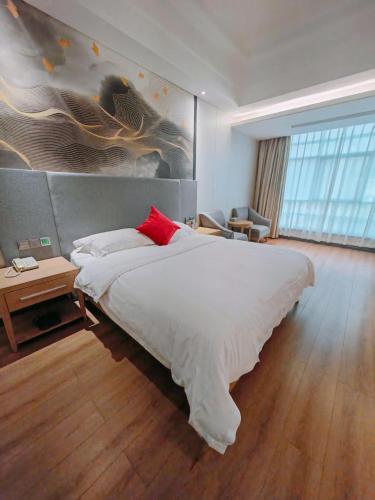 a bedroom with a large white bed with a red pillow at Ramada by Wyndham Zhangjiajie Tianmen Mountain in Zhangjiajie