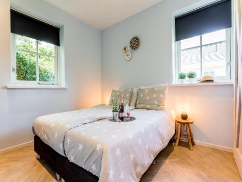1 dormitorio con 1 cama con sábanas blancas y 2 ventanas en Bungalow near Dutch Coast & Forest, en Noordwijk