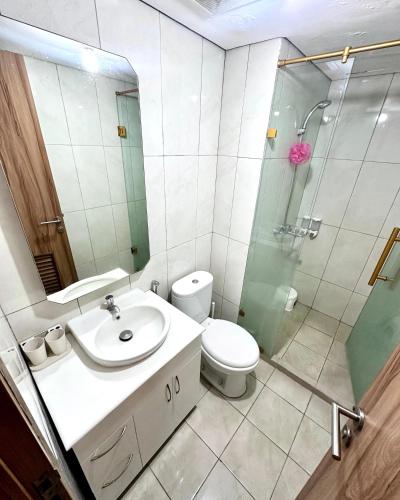 a bathroom with a toilet and a sink and a shower at Cozy 1BR Apartment with Home Office at The Nest Jakarta Barat in Jakarta