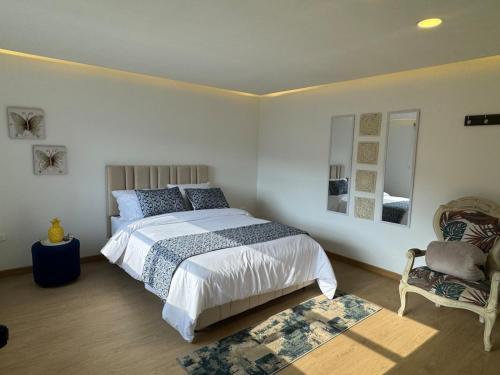 a bedroom with a large bed and a chair at El Encanto - La Trinidad, cabaña con jacuzzi in Duitama