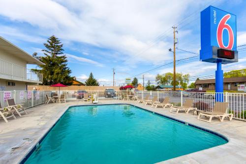 a swimming pool with chairs and a hotel sign at Motel 6-Klamath Falls, OR in Klamath Falls