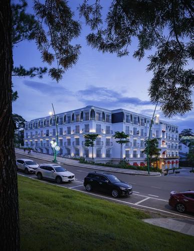 a large white building with cars parked in a parking lot at Golden Sun Hotel - Dalat in Da Lat