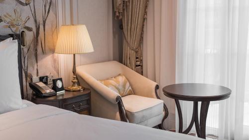 a hotel room with a chair and a table and a bed at Golden Sun Hotel - Dalat in Da Lat