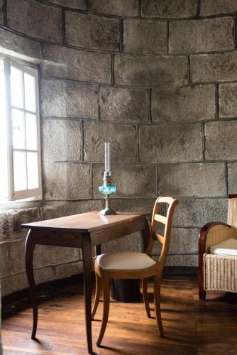 une table avec une bougie, deux chaises et un mur dans l'établissement Château de la Motte Beaumanoir, à Pleugueneuc