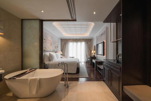a bathroom with a tub and a bedroom with a bed at Golden Sun Hotel - Dalat in Da Lat