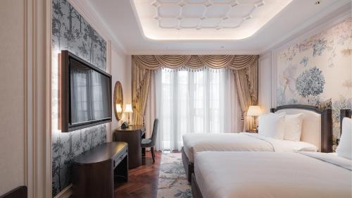 a hotel room with two beds and a desk at Golden Sun Hotel - Dalat in Da Lat