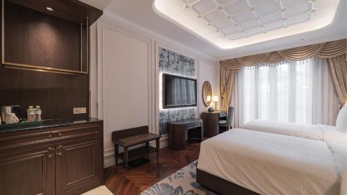 a bedroom with a bed and a television in a room at Golden Sun Hotel - Dalat in Da Lat