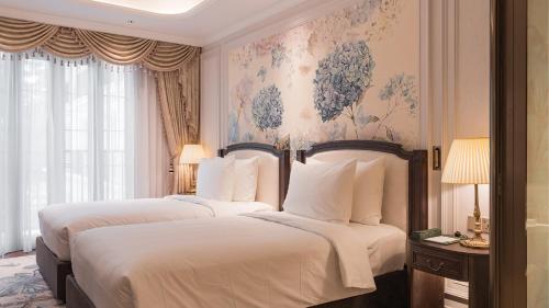 two beds in a hotel room with flowers on the wall at Golden Sun Hotel - Dalat in Da Lat