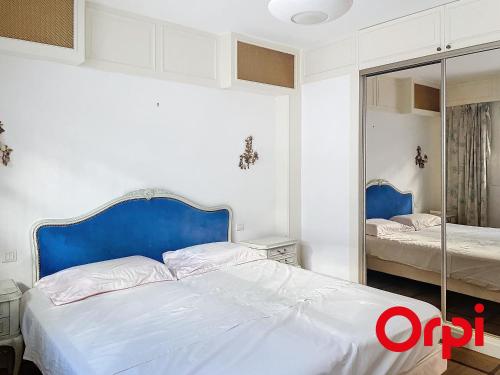 - une chambre avec un lit doté d'une tête de lit bleue et d'un miroir dans l'établissement Luxueux appartement avec piscine, climatisation, et WIFI, à 5 min de Monaco - FR-1-647-44, à Roquebrune-Cap-Martin