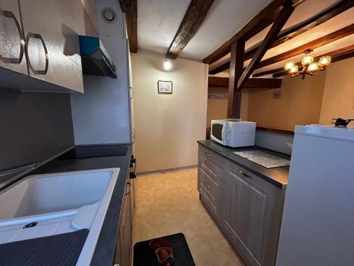 La cuisine est équipée d'un réfrigérateur blanc et d'un four micro-ondes. dans l'établissement Charmant T2 au centre de La Roche-Posay avec WIFI et parking gratuit - FR-1-541-163, à La Roche-Posay