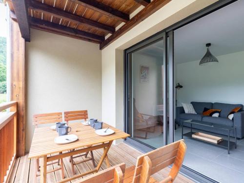 une table et des chaises en bois sur une terrasse avec un canapé dans l'établissement Appartement 4 personnes proche lac de Génos - FR-1-695-77, à Génos