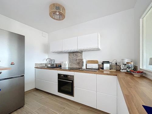 une cuisine avec des armoires blanches et un comptoir dans l'établissement Superbe T3 rénové entre port et plage avec parking privé - FR-1-715-109, à Mauguio