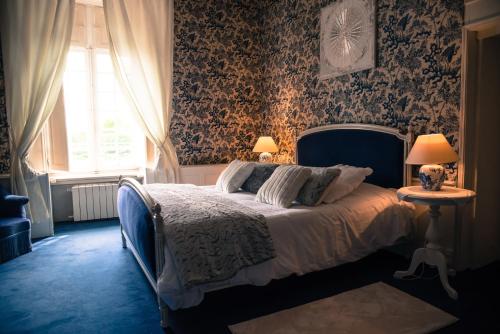a bedroom with a bed with floral wallpaper and a window at Château de la Motte Beaumanoir in Pleugueneuc