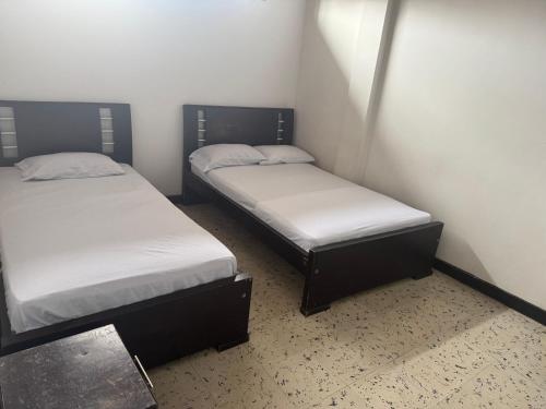 two beds in a small room withermottermott at Astoria Hotel Confortable in Pitalito