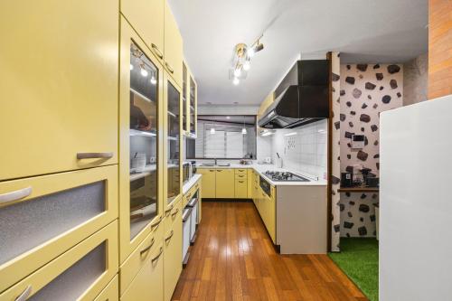 a kitchen with yellow cabinets and white appliances at 親子で遊べるボルダリングやボールプール付きの貸し切りアパート 国立駅徒歩4分 in Kunitachi