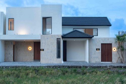 a large white house with a palm tree at Jena Island Villa in Cemagi